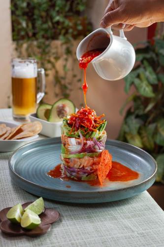 a person pouring sauce onto a plate of food at Hotel Plaza San Carlos in Xicotepec de Juárez