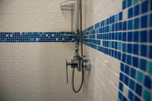 a shower in a bathroom with blue and white tiles at Хостел Рокет in Kaluga