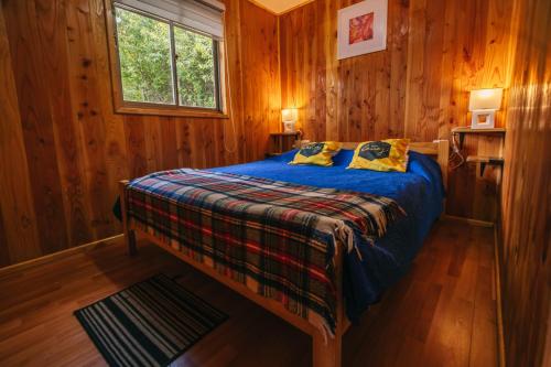 a bedroom with a bed in a wooden cabin at Cabañas Ruta Volcán Pucon in Pucón