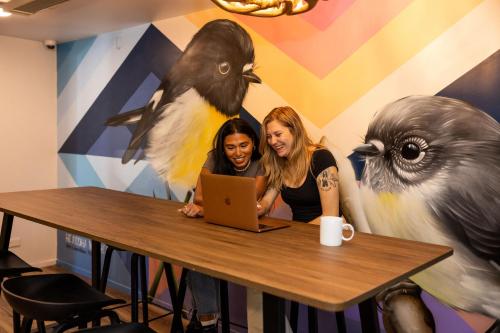 two women sitting at a table with a laptop at Haka House Queenstown Lakefront in Queenstown