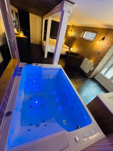 a large blue tub in the middle of a room at Le Cupidon & Spa in Pont-Sainte-Maxence