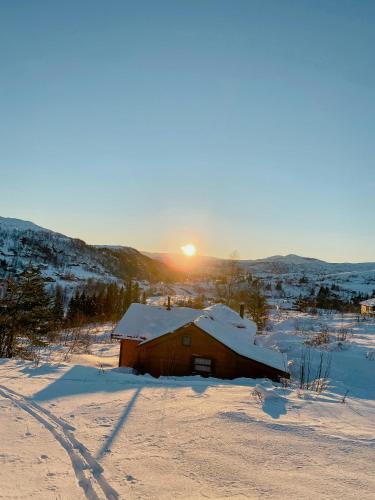 a barn in the snow with the sunset in the background at Mountain Cabin With Glacier Views in Norheimsund