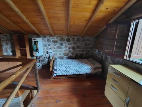 a bedroom in a log cabin with a bed in it at Stone Cabin, PETRA HAUS in Cuesta Blanca