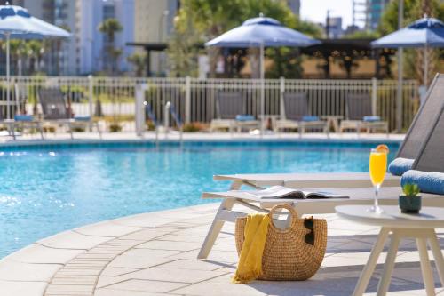 a swimming pool with a table and chairs and a purse at SpringHill Suites by Marriott Orange Beach Gulf Shores in Orange Beach