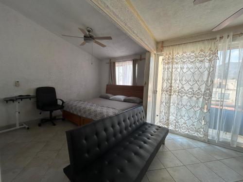 a bedroom with a bed and a chair and a window at Suite Villas Palmas Diamante in Acapulco