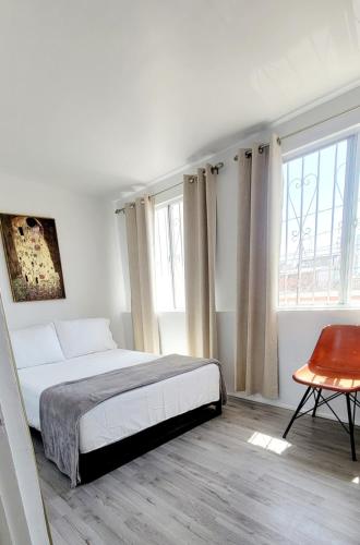 a bedroom with a bed and a table and windows at Tu Casa de Familia in Tijuana