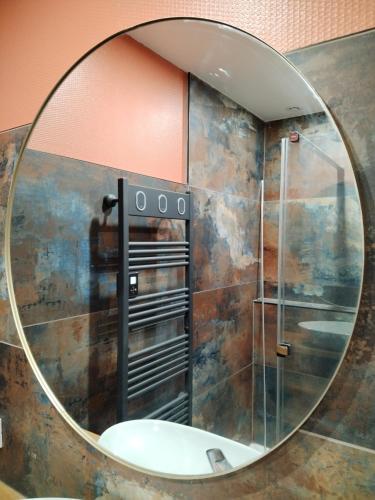 ein Spiegel in einem Badezimmer mit Dusche und Waschbecken in der Unterkunft Le3cent85 in Saint-Germain-Laval