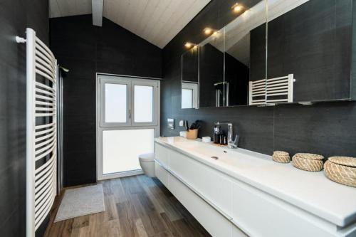 a bathroom with a large white sink and black walls at Bell Air-Plus in Les Hauts-Geneveys