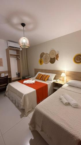 a bedroom with two beds and a chandelier at Pousada Mar da Vila in Cabo Frio