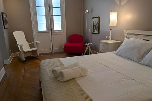 a bedroom with a white bed and a red chair at SHB - Beach House with Air Conditioning in Santos