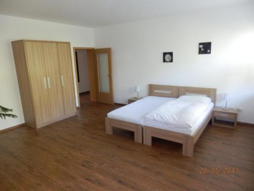 a bedroom with a white bed and a wooden floor at Apartmány Opletalka in Poděbrady