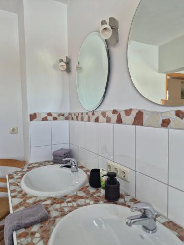 a bathroom with two sinks and two mirrors at haus nummer fünf - inklusive Chiemgau Karte in Siegsdorf