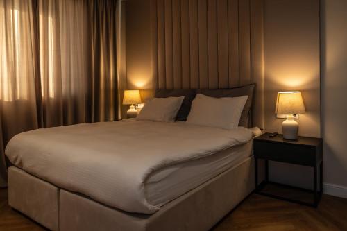 a bedroom with a large white bed with two lamps at Smarald Apartment in Satu Mare