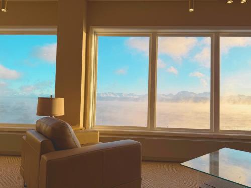 a living room with a chair and large windows at Land's End in Homer