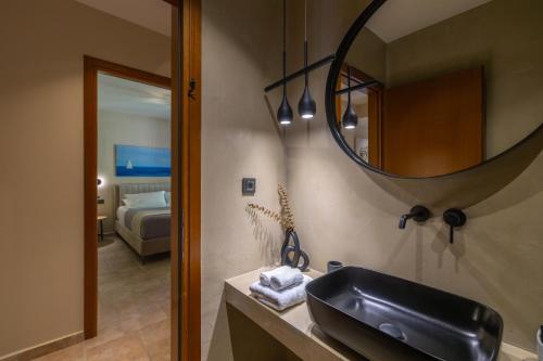 a bathroom with a sink and a mirror and a bed at Apeiron Villas - Olive Forest Apartment in Kefallonia