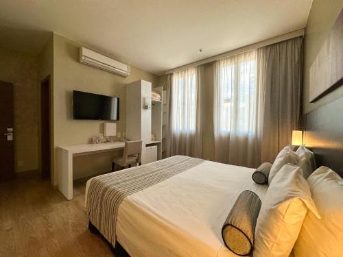 a hotel room with a bed and a desk at Grande Hotel Petrópolis in Petrópolis