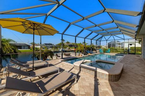 a swimming pool with chairs and an umbrella at Villa Somada in Cape Coral