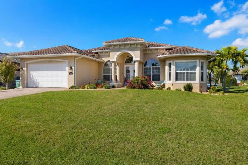 a large house with a green lawn in front of it at Villa Somada in Cape Coral