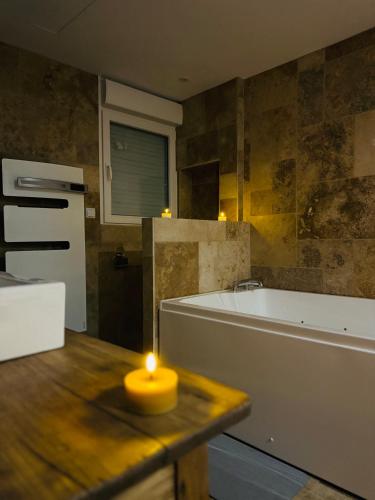 a bathroom with a candle on a table with a tub at Gîte le Nid Dhugava in Hem-Hardinval