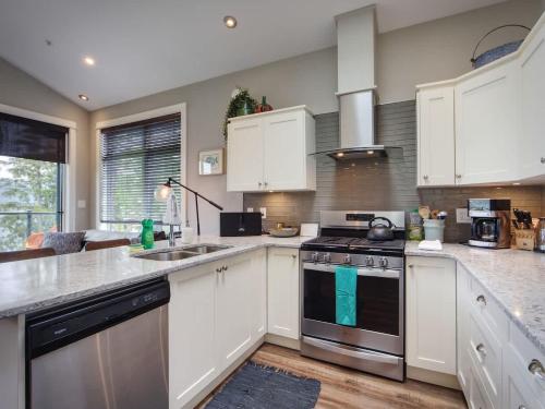 a kitchen with white cabinets and a stove top oven at Oceanfront Marina & Mountain views- pet friendly in Port Renfrew