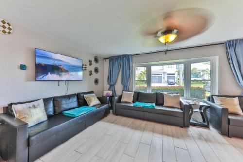a living room with a black leather couch at Island Paradise Villa RNT-01125 in Cape Coral
