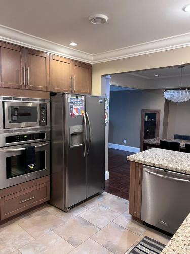 a kitchen with stainless steel appliances and wooden cabinets at Vancouver Comfort Home 10 min to YVR airport, Close to Downtown in Vancouver