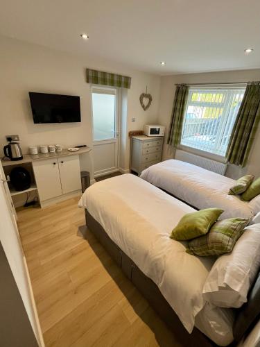a bedroom with two beds and a television in it at Acorns in Hordle