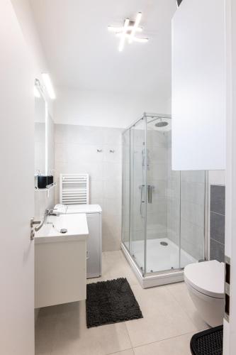 a white bathroom with a shower and a toilet at Eternity Apartment in Štúrovo