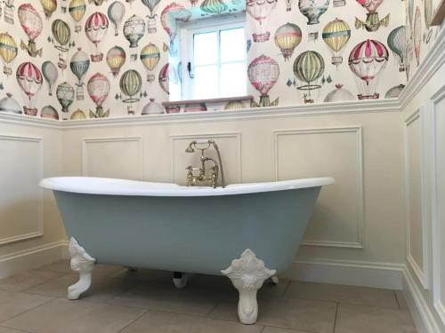 a bath tub in a bathroom with a wallpaper with hot air balloons at The Studio in Wisborough Green