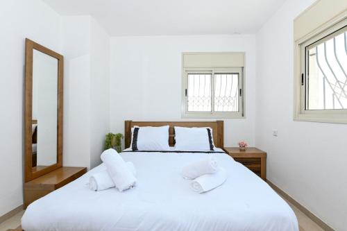 a white bedroom with a large bed and a mirror at גייט טו כנרת- פנטהאוז 4 חדרים עם שולחן ביליארד- ממד בדירה in Tiberias