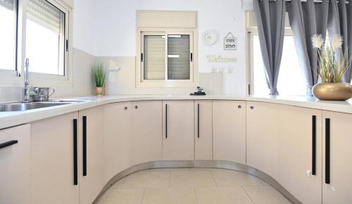 a kitchen with white cabinets and a sink and a window at גייט טו כנרת- פנטהאוז 4 חדרים עם שולחן ביליארד- ממד בדירה in Tiberias