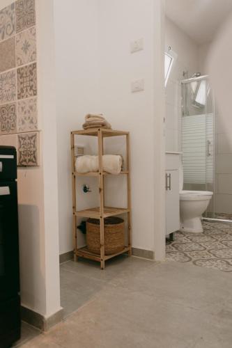 a bathroom with a toilet and a shelf with towels at אירוח משק 42 in Sheʼar Yashuv