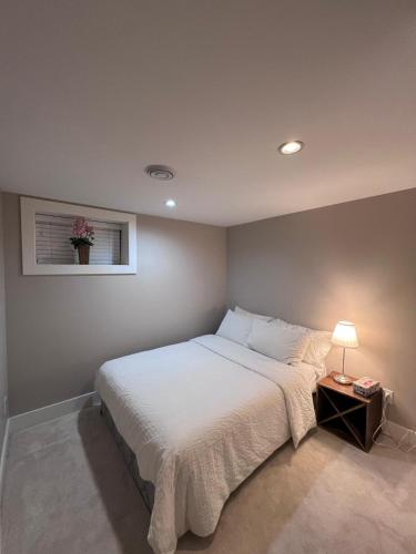 a bedroom with a white bed with a lamp and a window at Vancouver Comfort Home 10 min to YVR airport, Close to Downtown in Vancouver