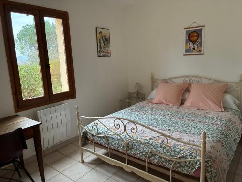 a bedroom with a bed with pink pillows and a window at Maisonette paisible à La Roque-Gageac in La Roque-Gageac
