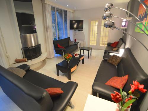 a living room with black couches and a fireplace at Quaint Villa in Doornspijk with Swimming Pool in Doornspijk