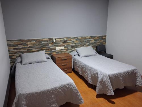 ein Schlafzimmer mit zwei Betten und einer Ziegelwand in der Unterkunft Pension Grilo in Padrón