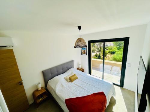 a bedroom with a bed and a large window at Villa Corail- Piscine privée- Corsu di Core in Conca