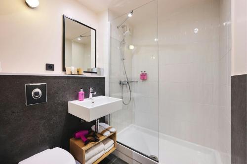 a white bathroom with a sink and a shower at Moxy Paris Bastille in Paris