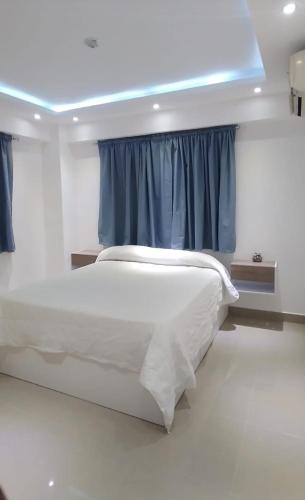 a bedroom with a white bed with blue curtains at Areito Apartament A&A in Juan López
