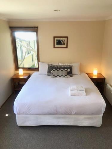 a bedroom with a large white bed with two lamps at Sun Apartments in Mount Hotham