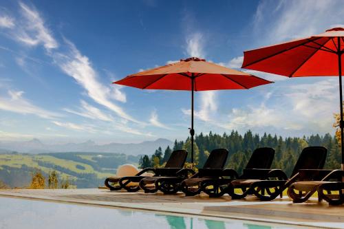 a group of chairs and umbrellas next to a swimming pool at Bergwald Panorama Suiten in Scheidegg