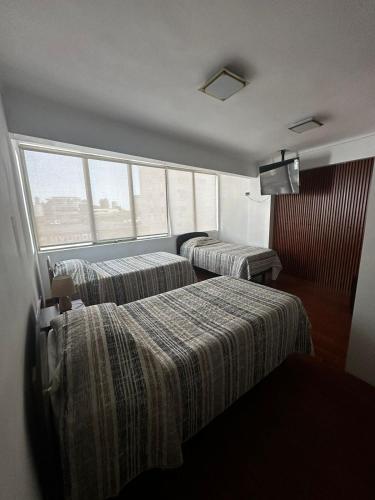 a hotel room with two beds and a window at Éclat Hotel Boutique in Iquique