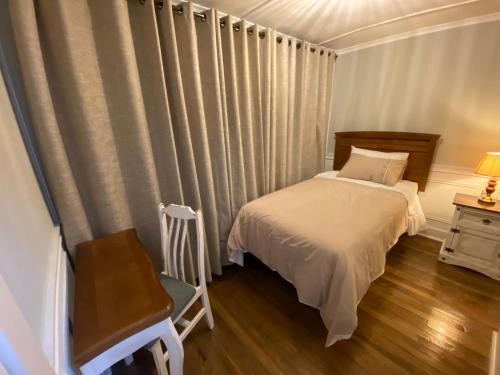 a bedroom with a bed and a chair and curtains at Barso Home Puerto Natales in Puerto Natales