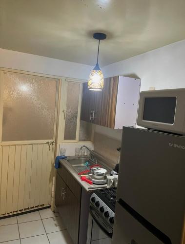 a small kitchen with a stove and a microwave at Departamento Entero en el Sur Facturamod in Santa Gertrudis