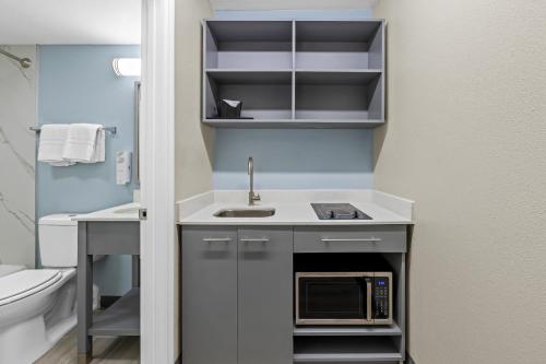 a small kitchen with a sink and a microwave at HomeTowne Studios by Red Roof Athens, TN in Athens
