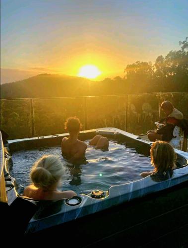 a group of people in a hot tub with the sunset at The House of the Rising Sun & Hot Spa in Gold Coast