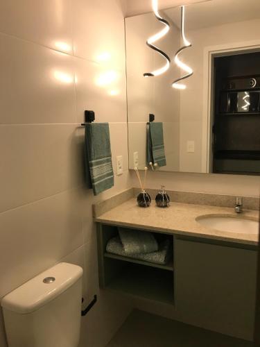 a bathroom with a sink and a toilet and a mirror at Studio Centro Curitiba in Curitiba