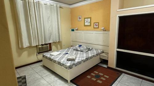 ein kleines Schlafzimmer mit einem Bett und einem Fenster in der Unterkunft Hotel Arsenal in São Gonçalo