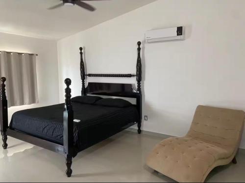 a bedroom with a black bed and a chair at Casa Chonita in Tecuala
