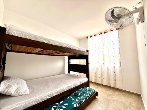 a bedroom with two bunk beds and a fan at Las Palmas Paraíso Ricaurte in Ricaurte